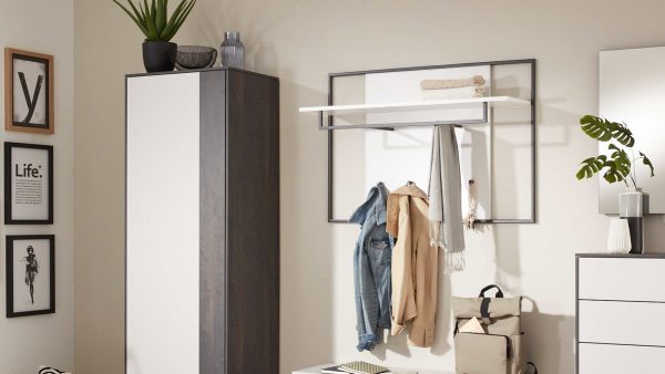 Ein moderner Flur mit der Interliving Garderoben Serie 6009 - Wandgarderobe 661910, gestaltet mit einer weißen Garderobe, einer Garderobe mit Jacke und Schals, einem beigen Rucksack, einer Topfpflanze und gerahmter Wandkunst in minimalistischen neutralen Tönen.
