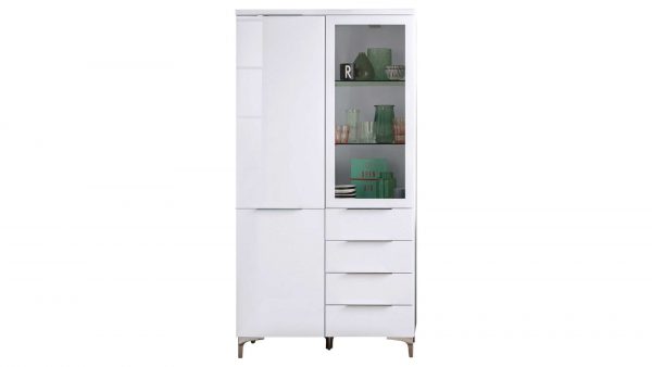 Die MAJA MÖBEL Vitrine Shino ist ein hoher, moderner, weißer Schrank mit Metallfüßen, vier Schubladen und zwei Türen - eine massiv, eine aus Glas -, auf dessen Einlegeböden Gegenstände wie Grünglas und Teller präsentiert werden können.