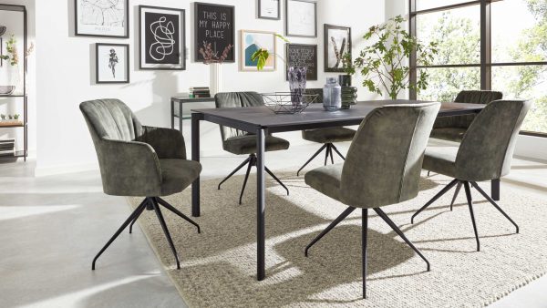 Modernes Esszimmer mit der Interliving Esszimmer Serie 5110 - Esstisch T0200, fünf grün gepolsterten Stühlen, einem großen Teppich, Wandkunst, Topfpflanzen und großen, lichtdurchfluteten Fenstern.