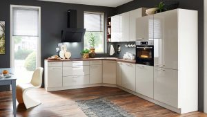 Moderne Küche mit glänzend weißen Schränken, eingebautem Ofen, schwarzer Dunstabzugshaube, Holzarbeitsplatte, Zimmerpflanzen und einem Teppich auf dunklem Holzboden. Durch zwei Fenster mit Jalousien strömt Sonnenlicht herein.