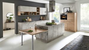 Moderne Küche mit grauen Schränken, einem Holzschrank, einer Insel mit einem ausziehbaren Holztisch und Einbaugeräten. Große Fenster lassen natürliches Licht herein, und Pflanzen und Deko-Akzente sorgen für Stil.