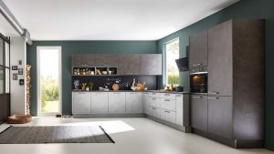 Moderne Küche mit mattgrauen Schränken, Geräten aus Edelstahl, schwarzem Backsplash und offenen Regalen für Geschirr und Gewürze. Große Fenster lassen viel natürliches Licht herein. Ein grauer Teppich liegt auf dem weißen Boden.