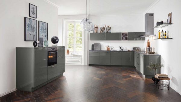 Moderne Küche mit glänzenden grauen Schränken, Einbaubackofen, Holzarbeitsplatten und offenen Regalen. Ein großes Fenster lässt natürliches Licht herein, das den Holzfußboden im Chevron-Muster und die minimalistische Einrichtung hervorhebt.
