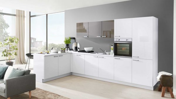 Moderne Küche mit glänzend weißen Schränken, einem eingebauten Backofen und einer grauen Aufkantung; Arbeitsplatten und Pflanzen schmücken den Raum. Große Fenster sorgen für natürliches Licht, und ein Sofa ist teilweise im Vordergrund zu sehen.