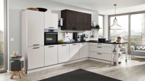 Moderne Küche mit weißen Schränken, schwarzen Arbeitsplatten, einem eingebauten Ofen, einer Kaffeemaschine und einem Herd. Große Fenster bieten einen Blick auf die Stadt und eine Frühstücksbar mit Hockern unter einer Hängelampe. Helle Holzböden ergänzen den Raum.