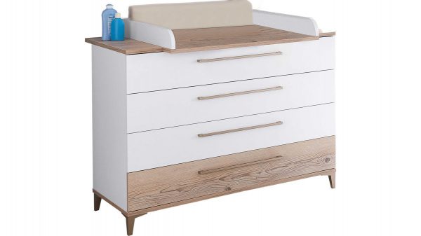 Das PAIDI Babyzimmer Katrin Wickelkommode mit Aufsatz hat Holzbeine und -kanten, weiße Schubladen, eine beige Wickelauflage oben und zwei Flaschen auf der linken Seite.