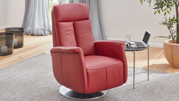 Der Modulmaster MM-PN1035 - Relaxsessel 1SDCL D2, ein moderner roter Lederdrehsessel, steht auf einem grauen Teppich neben einem kleinen runden Tisch mit einem Laptop, einem Glas Wasser und Kopfhörern in einem hellen Raum mit Holzboden und Zimmerpflanzen.